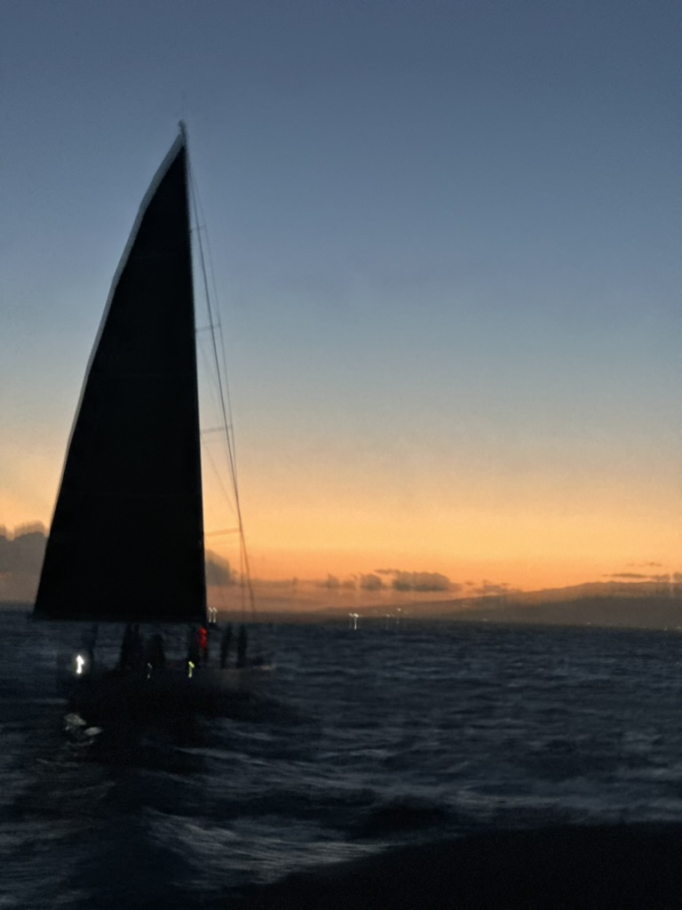 A sailboat finishing at sunset off Diamond Head